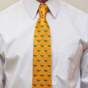 Man wearing a t-rex themed tie in light orange and green with a white dress shirt